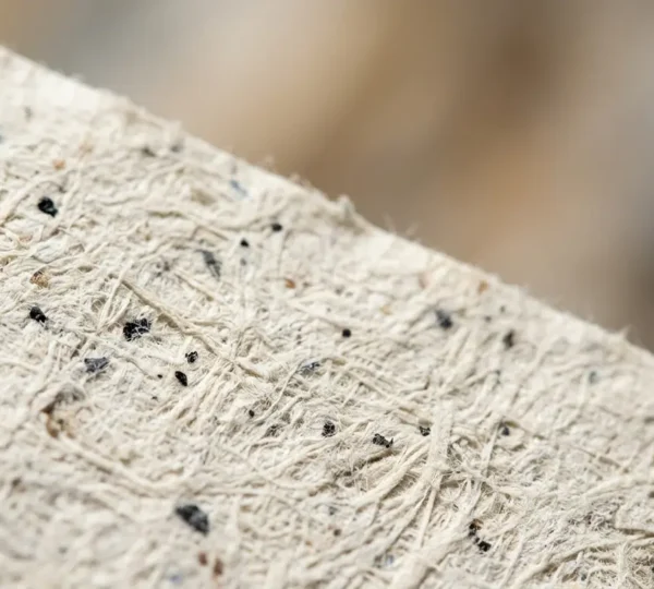 Gros plan macro sur la texture d'un papier recyclé PCW révélant les fibres et les imperfections caractéristiques