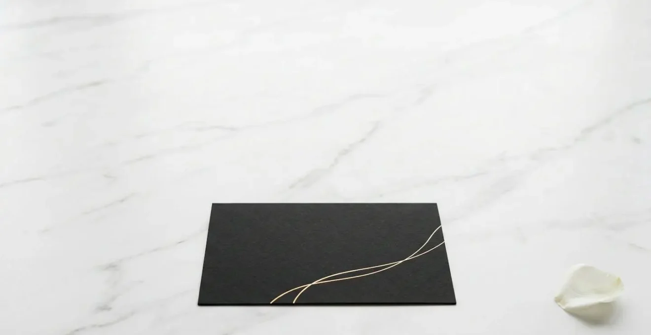 Vue minimaliste montrant l'équilibre entre surfaces mates et détails dorés sur une invitation
